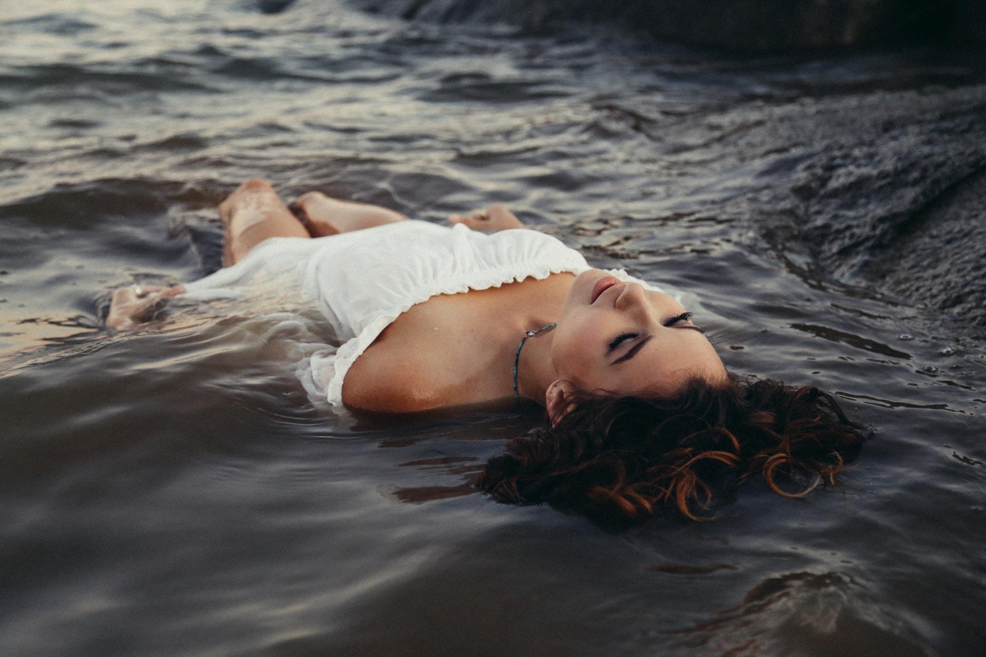 woman clothed laying in waves