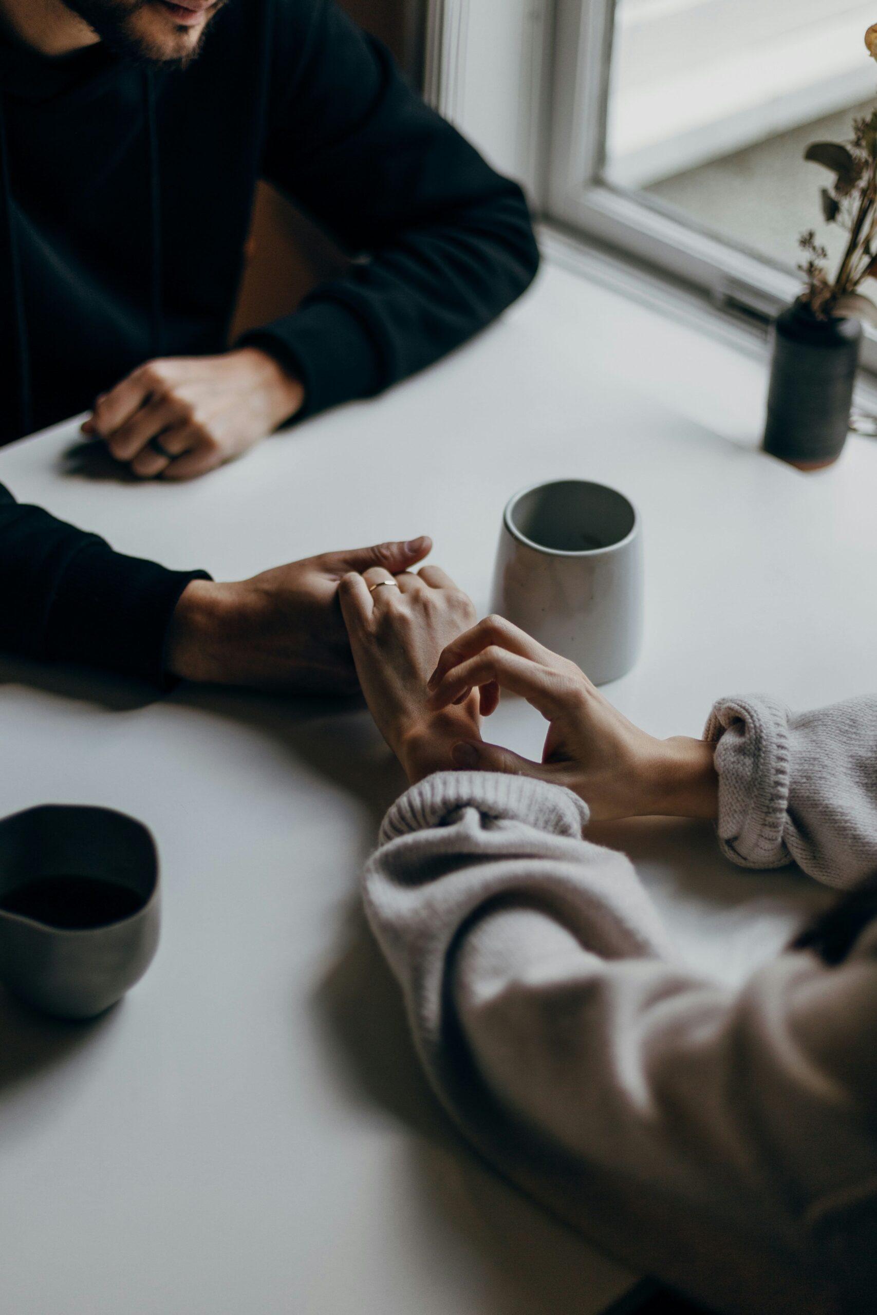 couple talking and holding hands over a table.